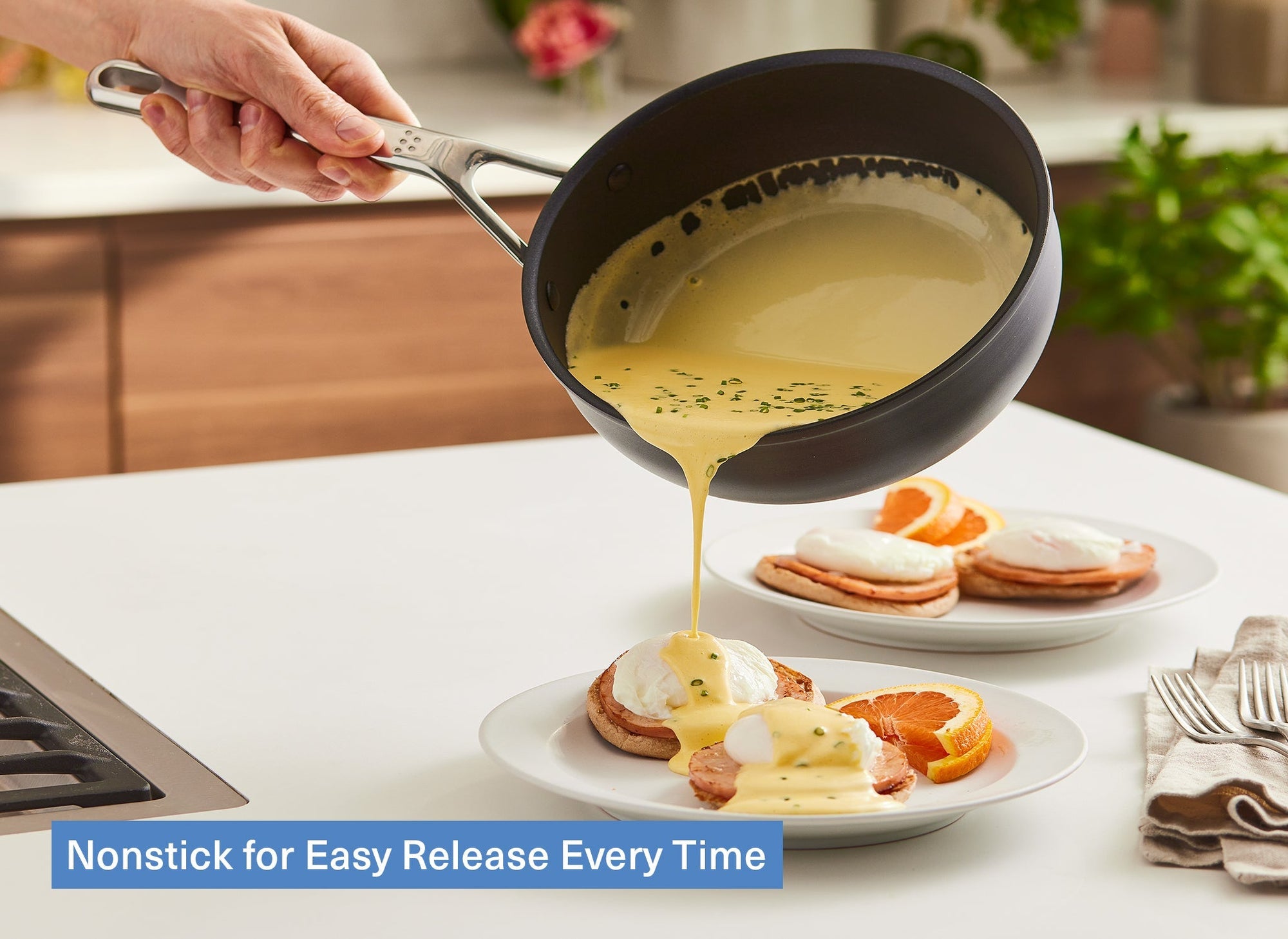 A chef pours Hollandaise sauce out of a Misen Nonstick Saucier onto a plate of eggs benedict on a kitchen counter. A caption reads: “Nonstick for Easy Release Every Time.”