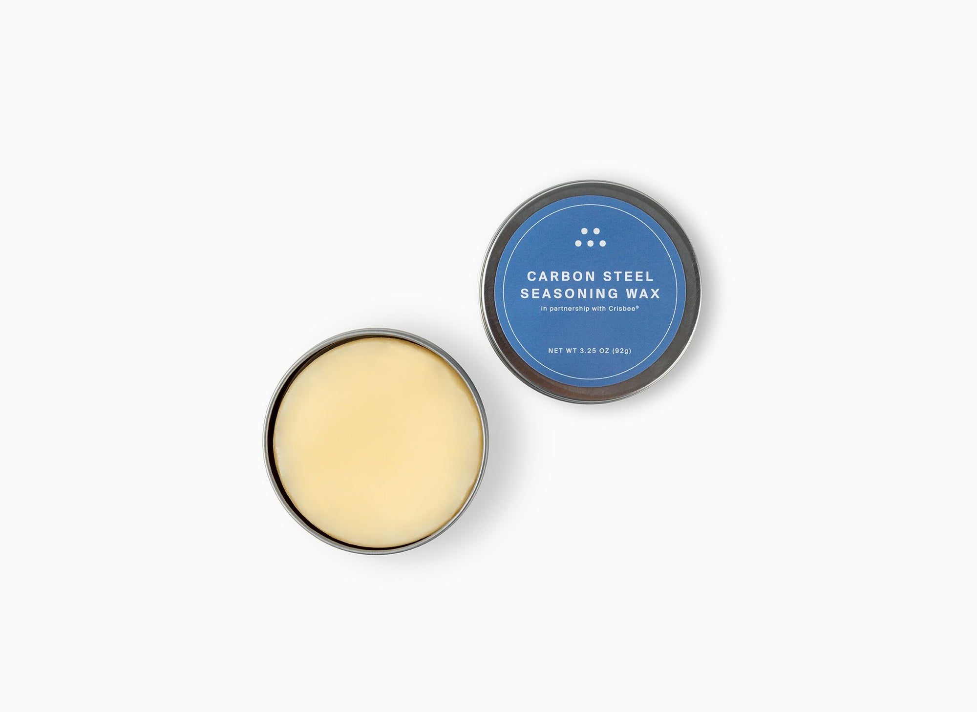 Misen Carbon Steel Seasoning Wax tin seen from above with blue lid removed to reveal pale yellow seasoning wax puck.