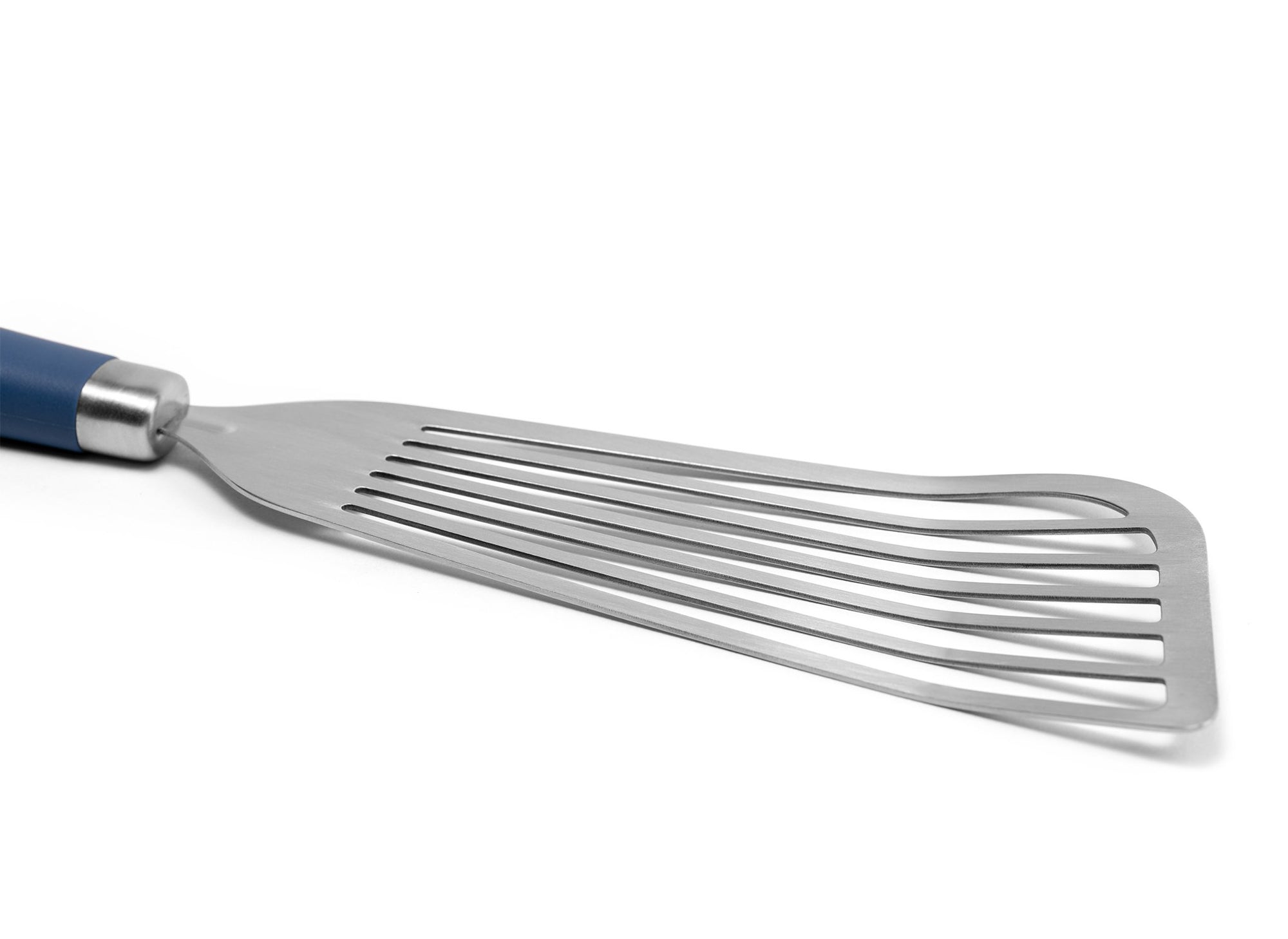 {{stainless-steel-blue}} A close view of the Blue Misen Metal Fish Spatula’s slotted head. It’s long, slightly flared, and made of bare steel.
