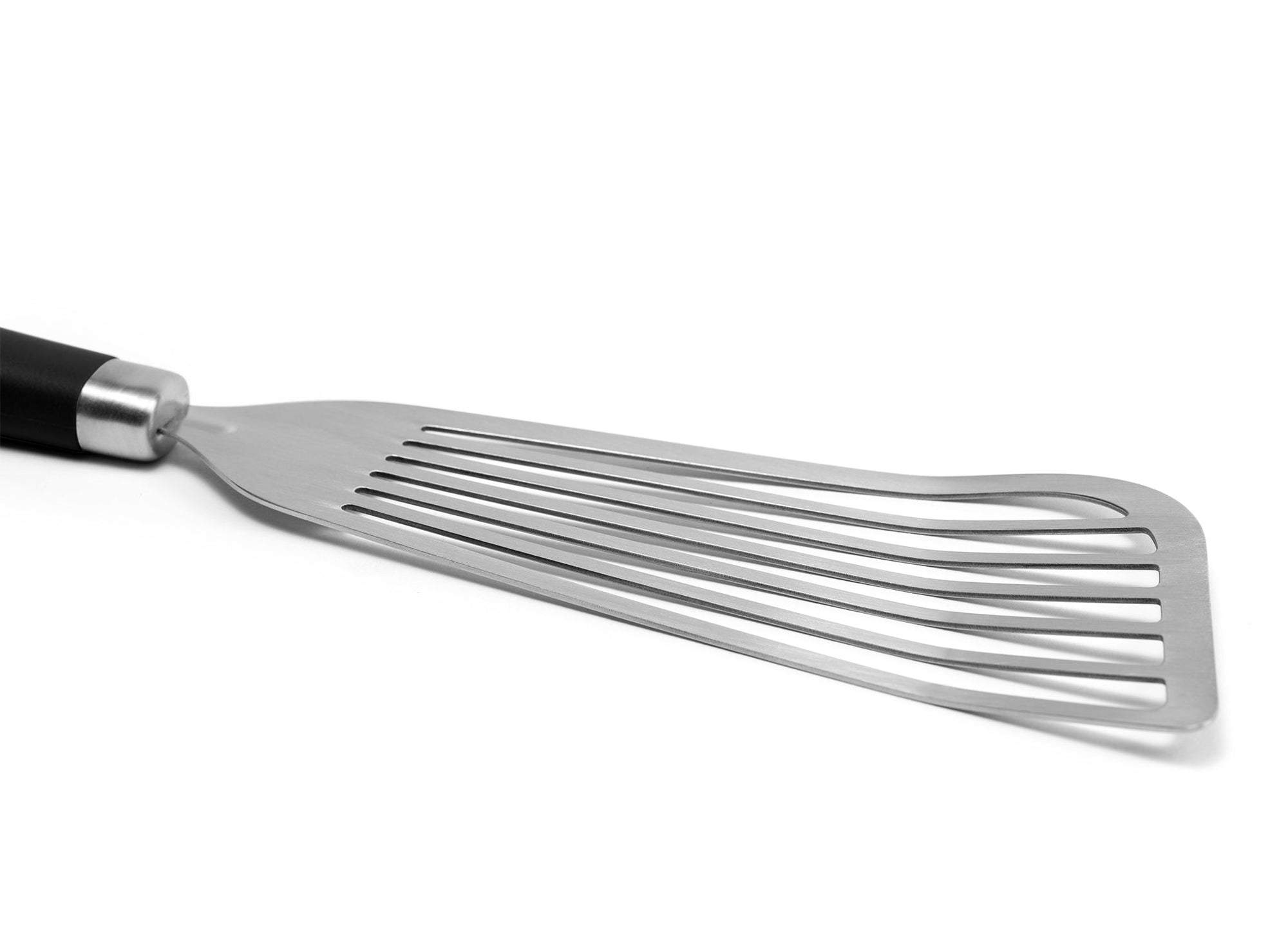 {{stainless-steel-black}} A close view of the Black Misen Metal Fish Spatula’s slotted head. It’s long, slightly flared, and made of bare steel.