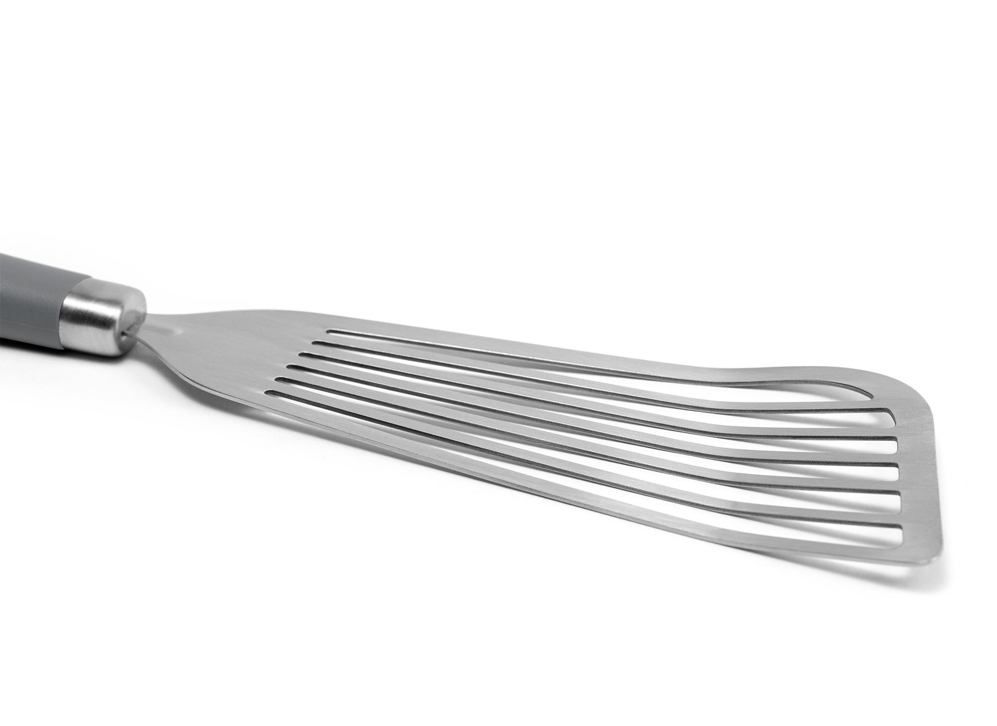 {{stainless-steel-gray}} A close view of the Grey Misen Metal Fish Spatula’s slotted head. It’s long, slightly flared, and made of bare steel.