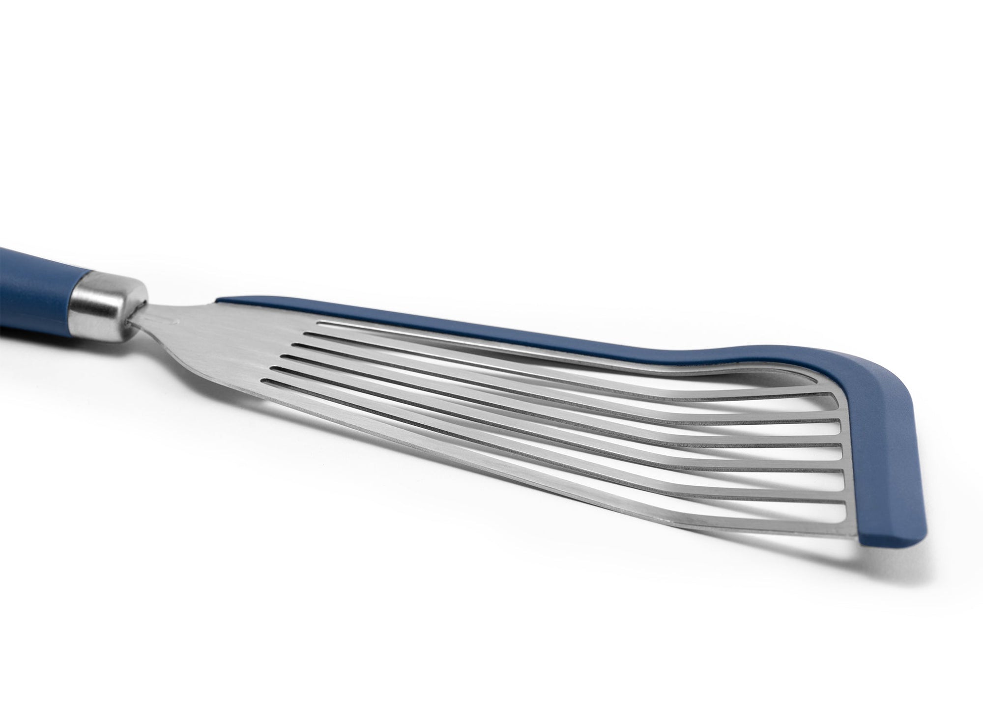 {{blue}} A close view of the Blue Misen Silicone Fish Spatula’s slotted metal head, showing a blue silicone lining along two edges.
