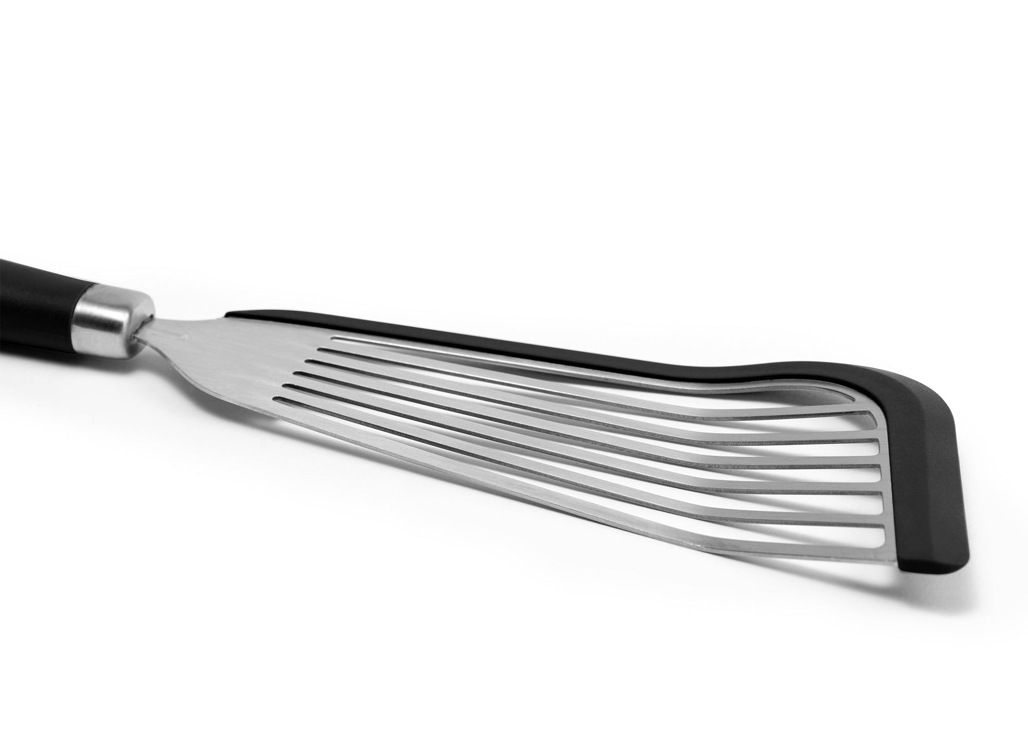 {{black}} A close view of the Black Misen Silicone Fish Spatula’s slotted metal head, showing a black silicone lining along two edges.