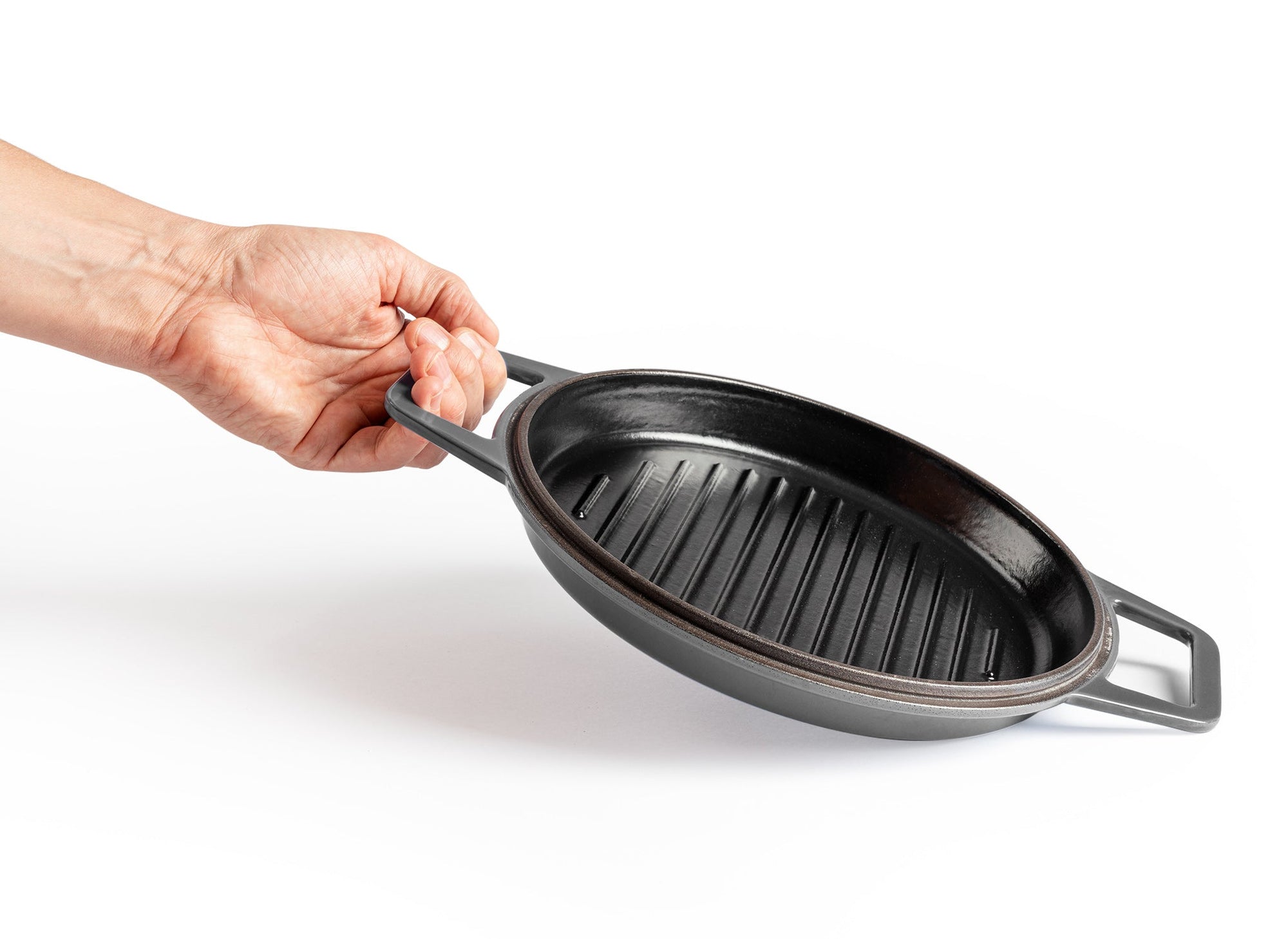 {{black,7-qt-black,9-qt-black}} A hand lifts up a Black Misen Enameled Cast Iron Grill pan by one of its two side handles.