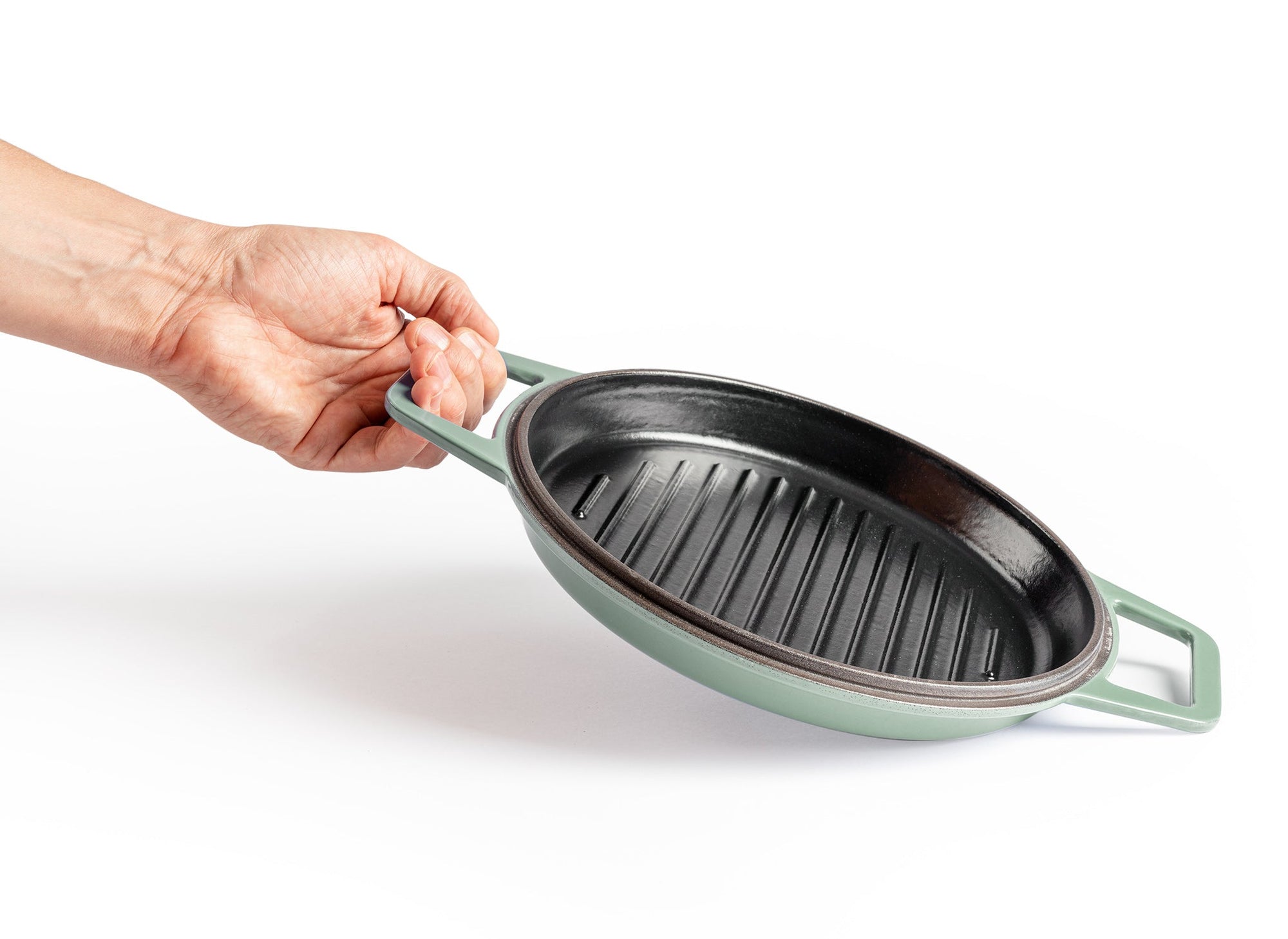 {{green,7-qt-green,9-qt-green}} A hand lifts up a Green Misen Enameled Cast Iron Grill pan by one of its two side handles.