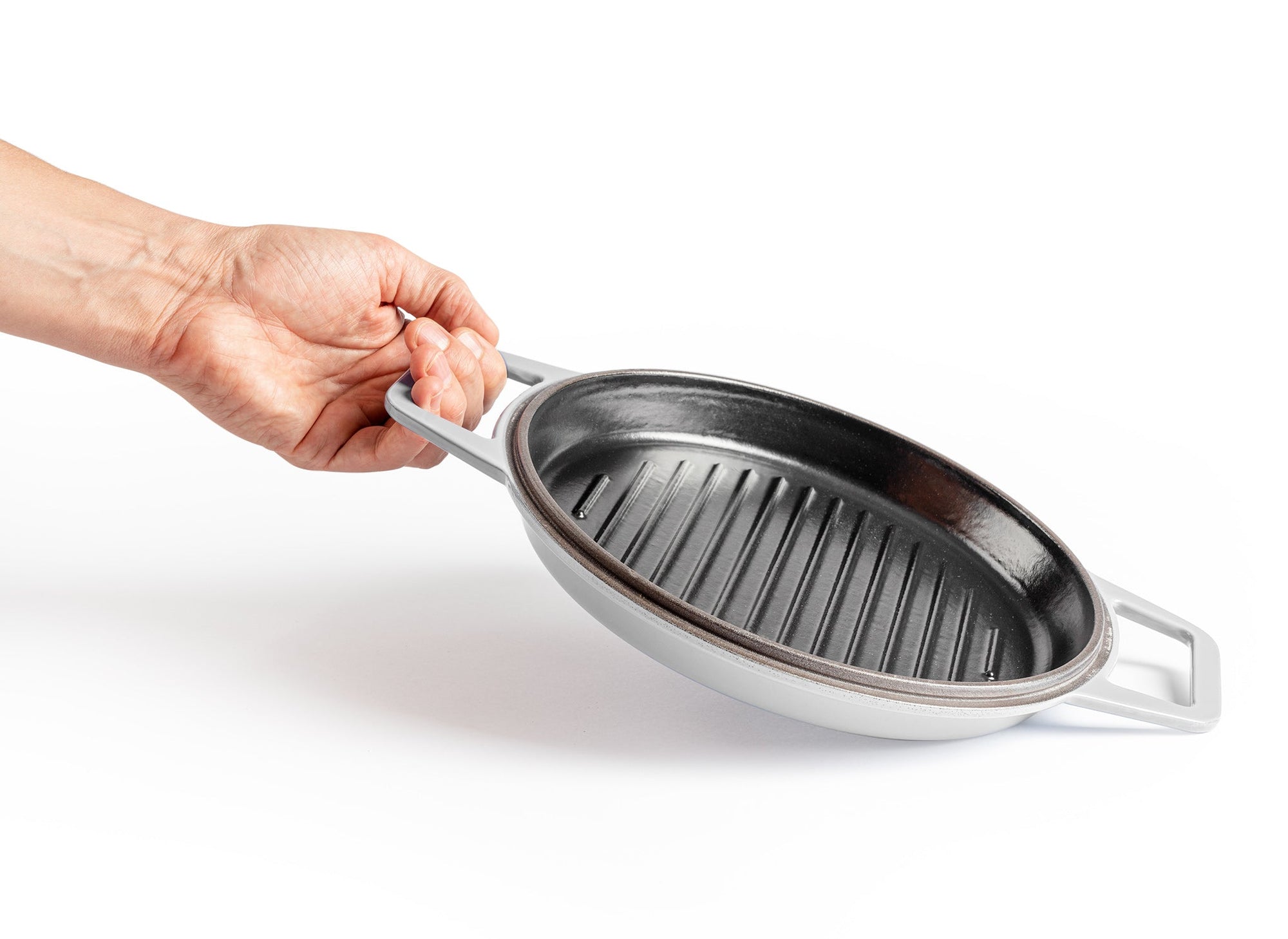 {{gray,7-qt-gray,9-qt-gray}} A hand lifts up a Gray Misen Enameled Cast Iron Grill pan by one of its two side handles.