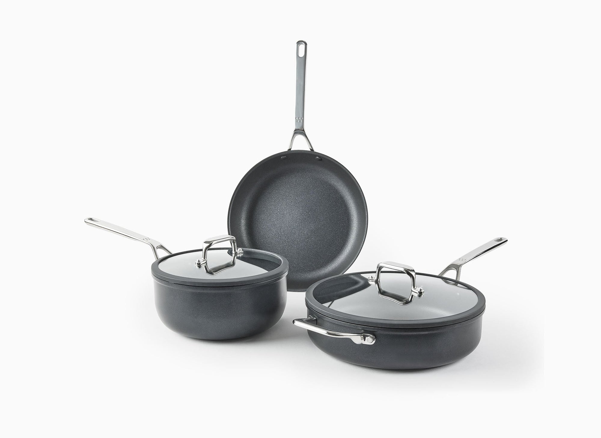 The Misen 5-Piece Essentials Cookware Set on a white background, with most pieces visible: the 12-inch Nonstick Pan, Nonstick Sauté, and Nonstick Saucier, with lids.