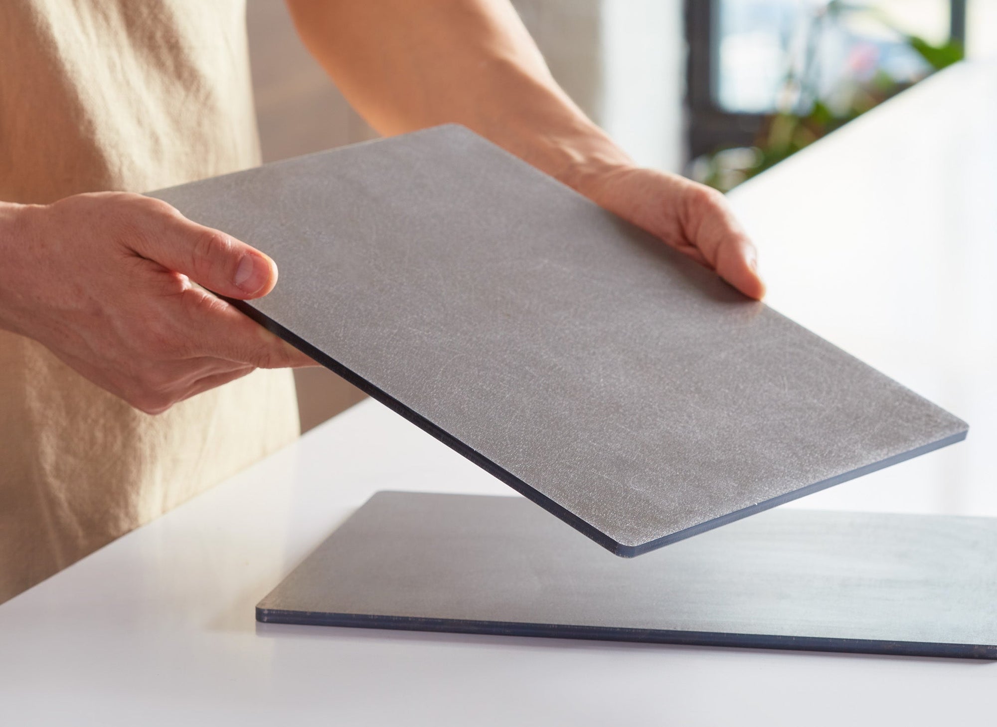 {{single, 2-pack, 4-pack}} A chef lifts a Misen Oven Steel with both hands, while a second Oven Steel is visible on a countertop in the background.