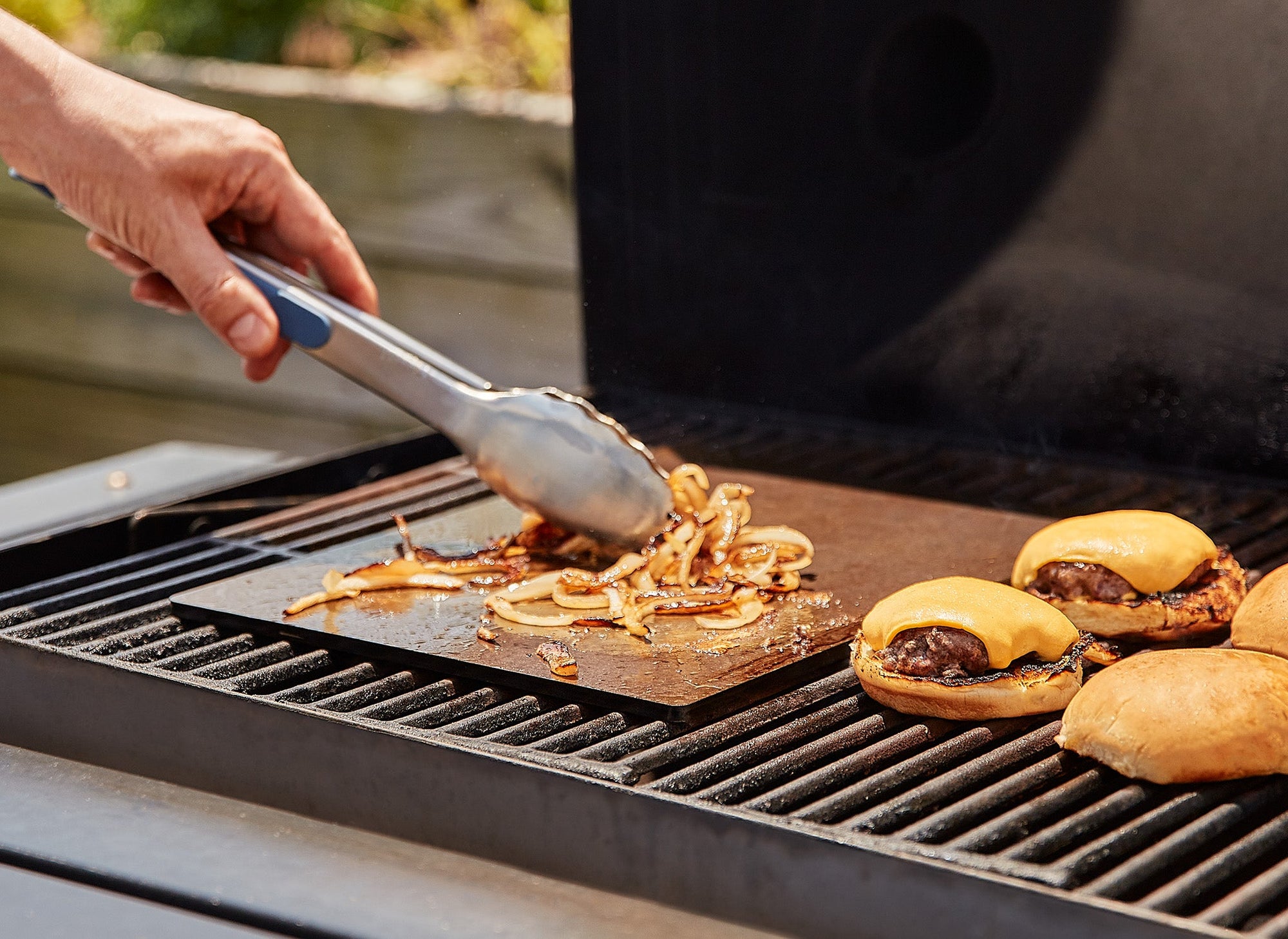 {{single, 2-pack, 4-pack}} A Misen Oven Steel on an outdoor grill caramelizes thin onion slices for waiting cheeseburgers.