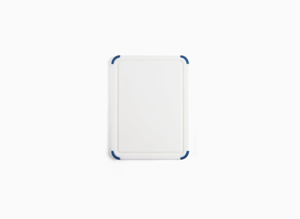 A small Misen Plastic Cutting Board seen from directly overhead, with juice groove and blue corner grips visible.