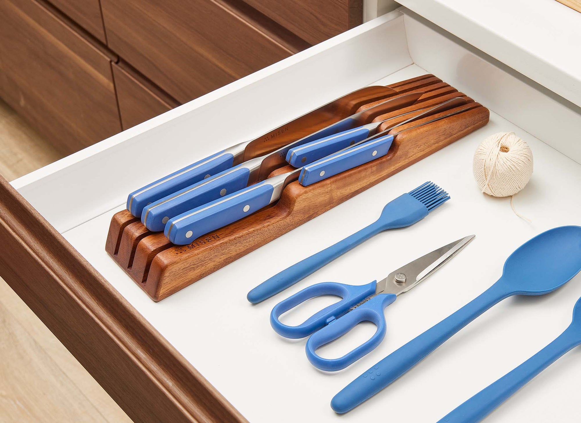 {{ash,walnut}} Walnut Misen In-Drawer Knife Storage containing five blue Misen Knives sits inside an open kitchen drawer, with other Misen Prep Tools nearby.