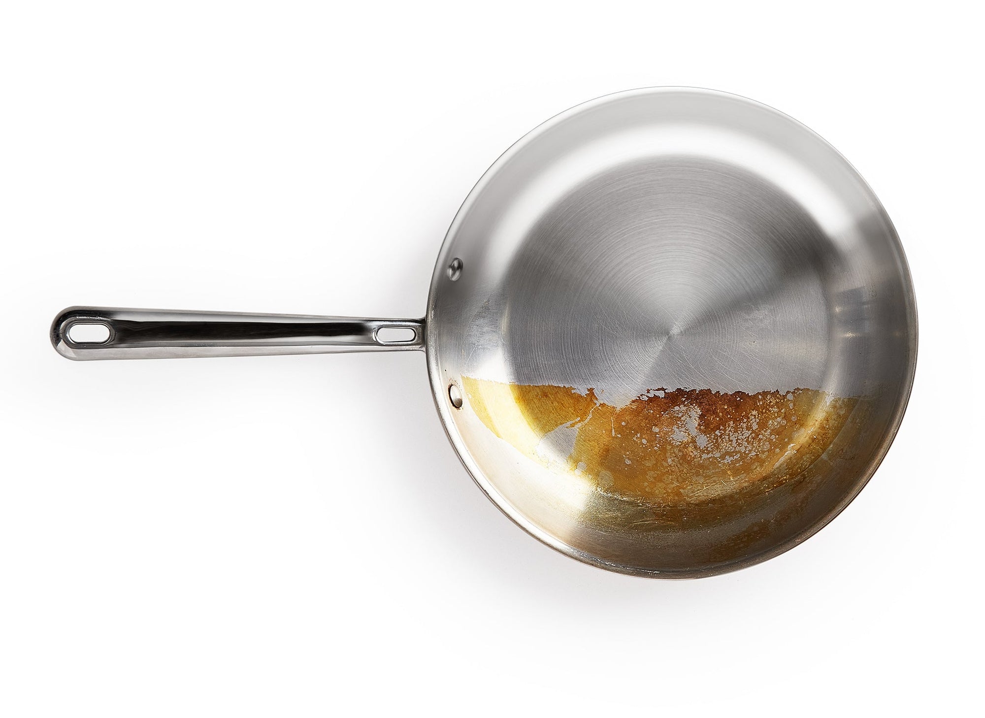 {{12-oz}} A top-down view of a partly cleaned Misen Stainless Steel Skillet. Half the pan is stained brown and the other side shines like new. 