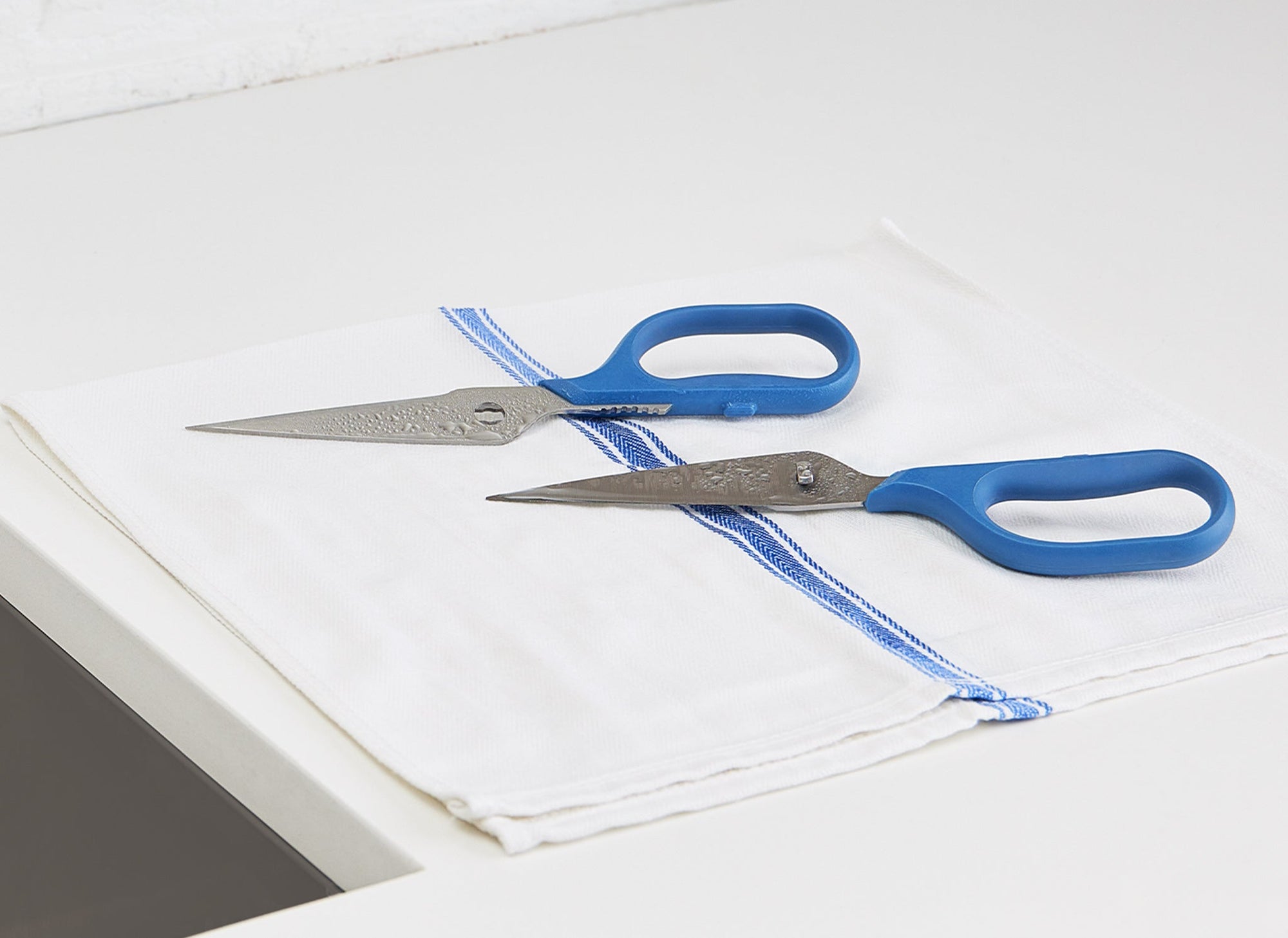 {{blue,black,gray,green,red}} Detached halves of Blue Misen Kitchen Shears drying on a kitchen towel.