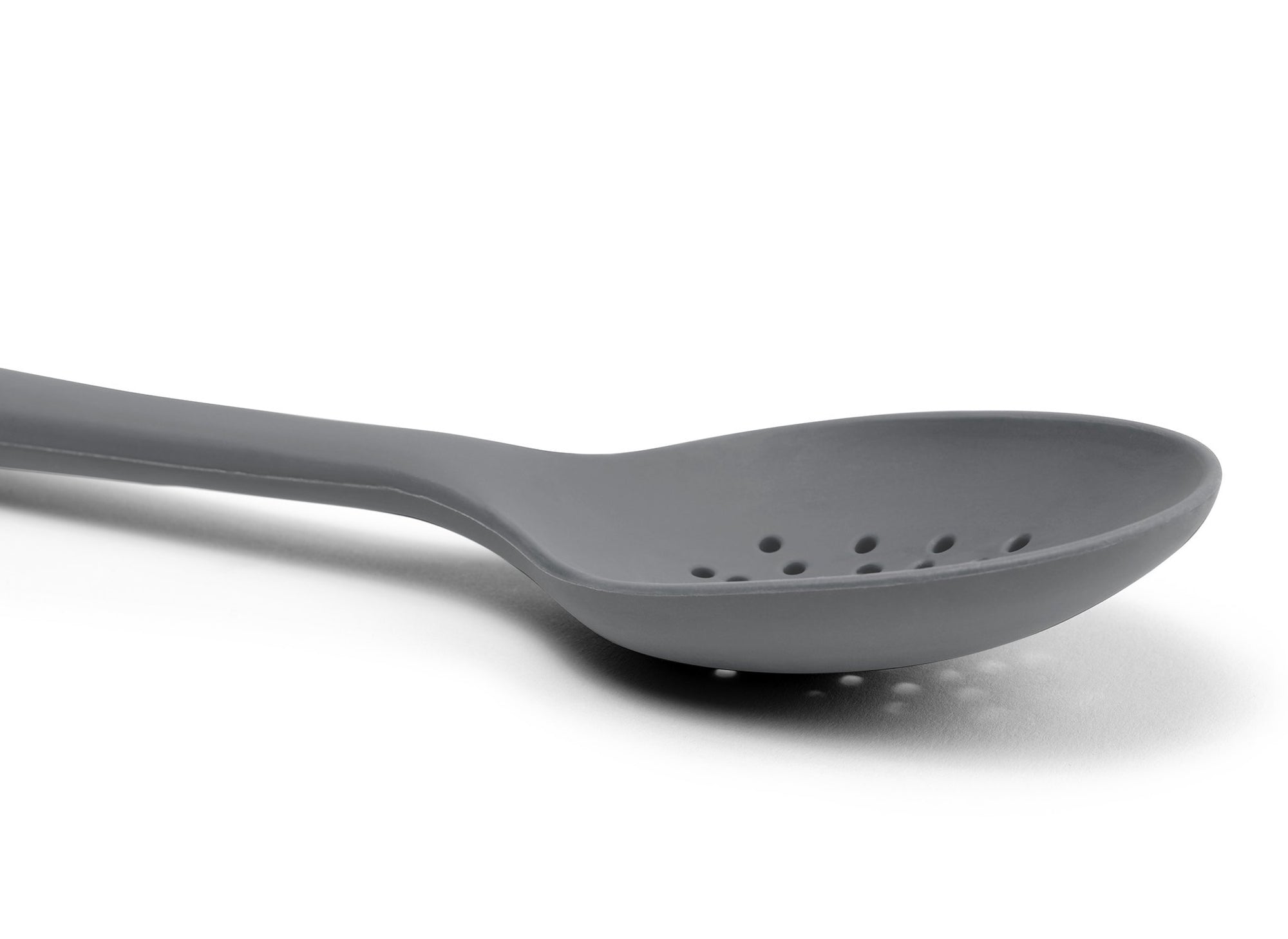 {{gray}} A close view from the side of a Grey Misen Slotted Spoon’s curved head with drainage holes visible on a white background.