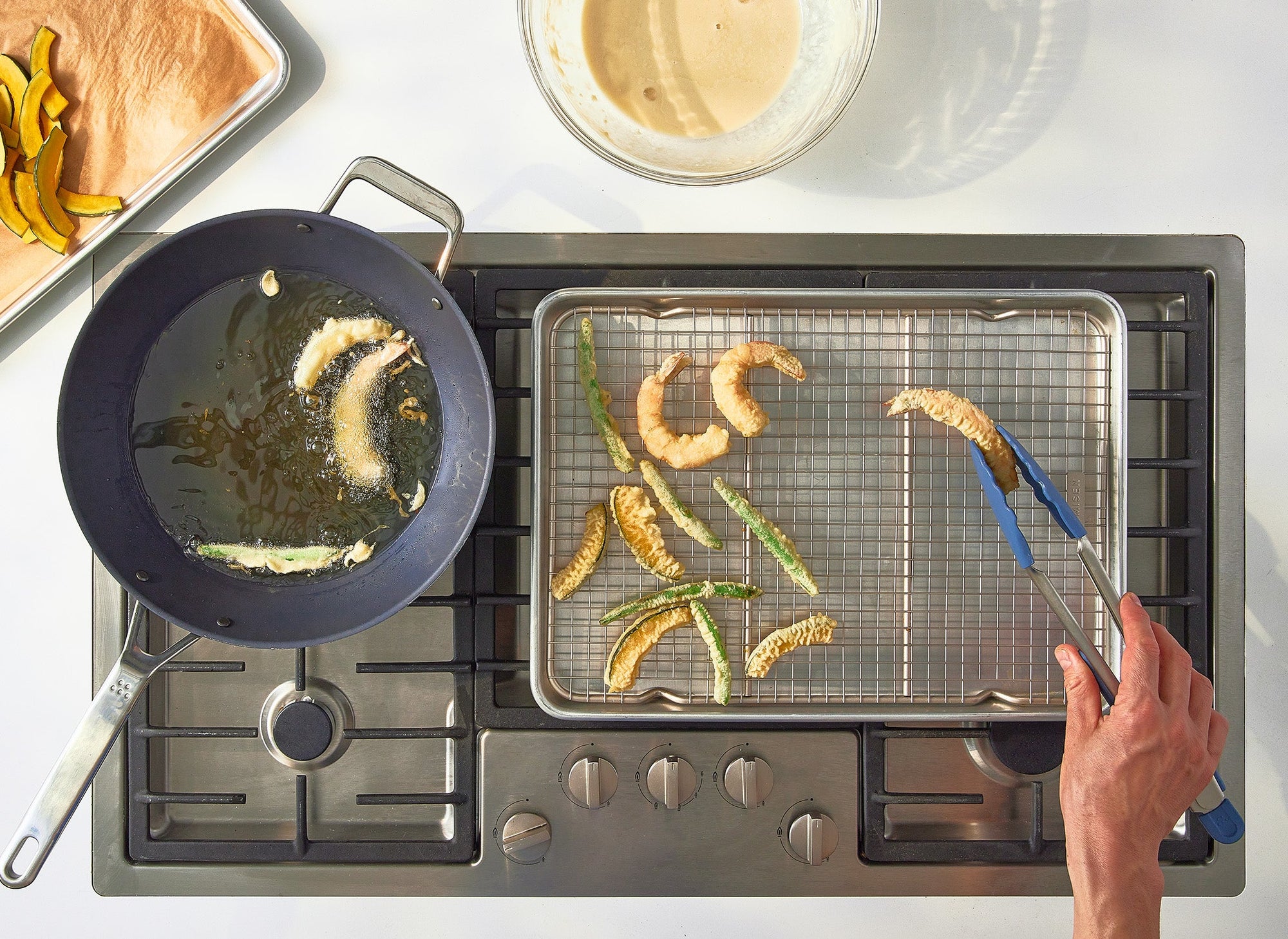 {{quarter-sheet,half-sheet,small-set,large-set}} A hand uses Misen Tongs to remove freshly-fried vegetables from a Misen Wok to place on a Misen Wire Rack within a Misen Sheet Pan. The Wok, Wire Rack and Sheet Pan rest on a stovetop.